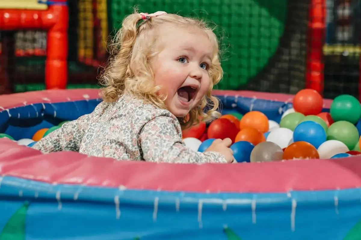 A delighted little girl in a Happy Town ball pit
